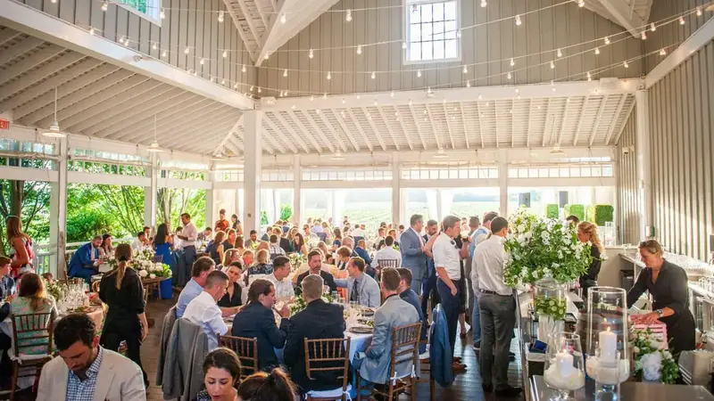 Guests at long tables under string lights in Bedell's white open-sided pavilion