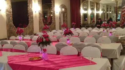 The lodge ballroom set for a party, with round tables in white and pink linens, chandeliers and mirrored stone walls