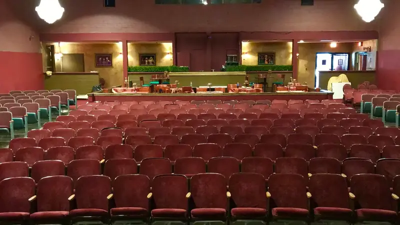 View from the stage across rows of red theater seats under chandeliers