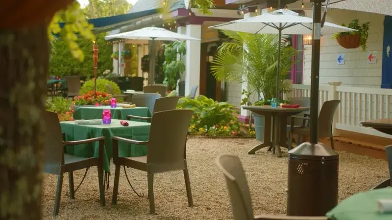 The Cooperage Inn's garden patio with green-clothed tables, white umbrellas and potted plants