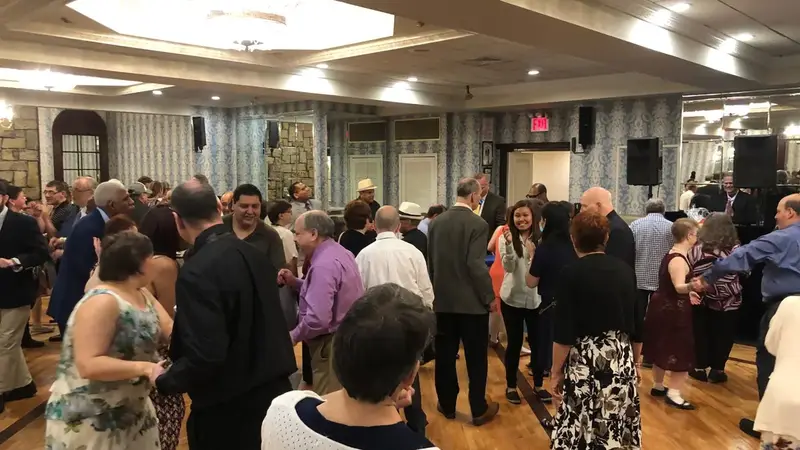 Adults dancing on a wooden floor in a banquet hall at a social dance