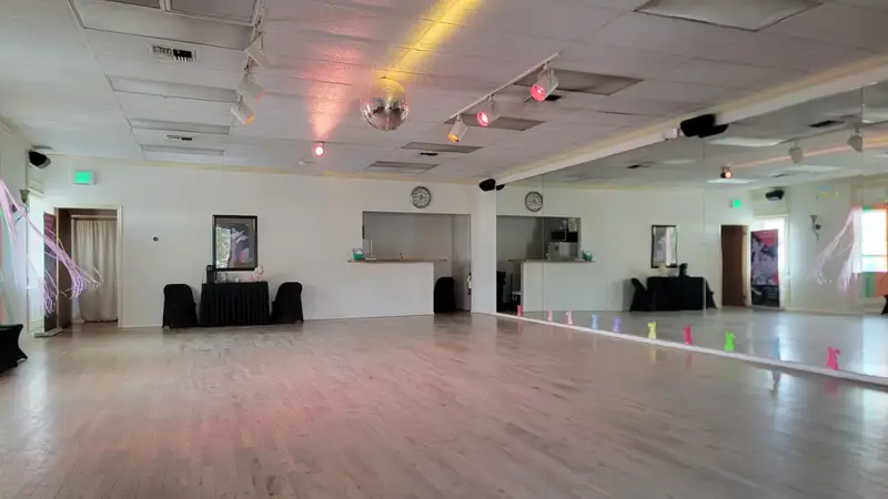 The empty studio: a large light wood dance floor, a mirrored wall and a disco ball hanging from the ceiling