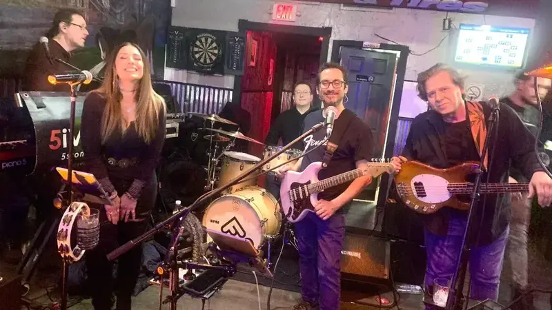 FiveStone on a small bar stage: a woman singer, guitarist, bassist and drummer smiling behind their instruments