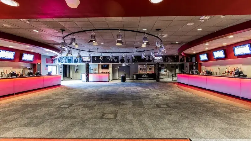 The empty main lobby at Westbury Music Fair with pink-lit bars on both sides and photos of past performers on the far wall