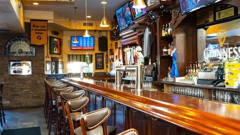 The long wooden bar at Flanagan's with padded stools, beer taps and TVs above