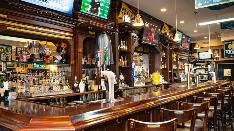 Another view of Flanagan's bar with rows of bottles, wood shelves full of signs and a curved bar top