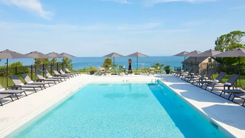 The hotel's long outdoor pool with lounge chairs and umbrellas, looking out to the Sound