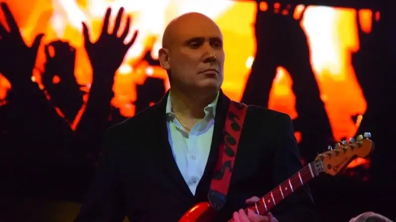 In The Groove's guitarist playing a red electric guitar in front of a glowing orange screen