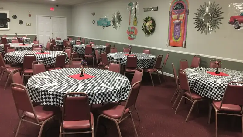 The hall with round tables in black-and-white checkered cloths, pink chairs and retro decorations on the walls