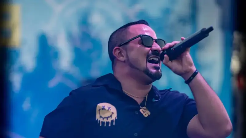 Krush lead singer in sunglasses singing into a microphone under blue stage lights