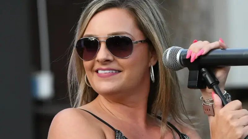 Krush female singer in sunglasses smiling and holding a microphone
