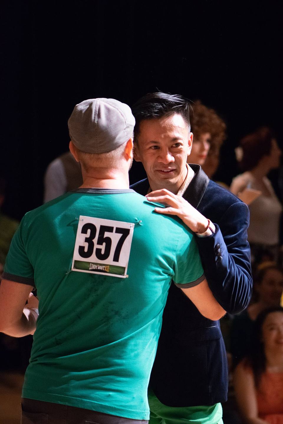Two men in a cap and a jacket swing dancing together. Anyone can lead or follow.