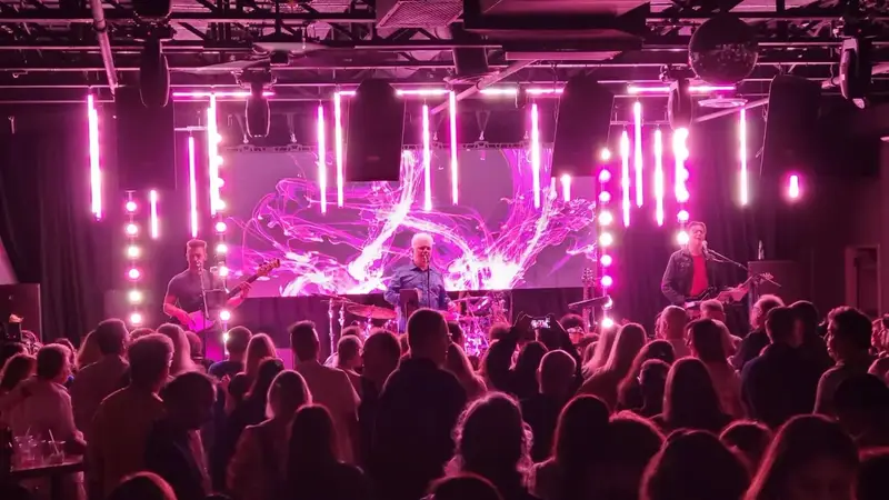 Lovesong on stage in bright pink light with a big video screen behind them while a crowd dances on the floor