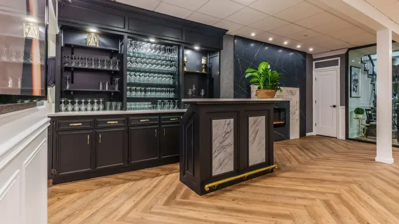 A black wood bar with glassware shelves in a bright room with a herringbone wood floor at Mezza Luna