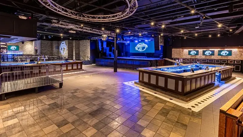 Wide view of the Mulcahy's ballroom: a large open tiled floor, a square island bar and the stage at the back