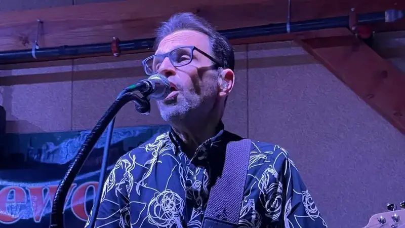 Nitework's guitarist singing into a microphone while playing an electric guitar on stage
