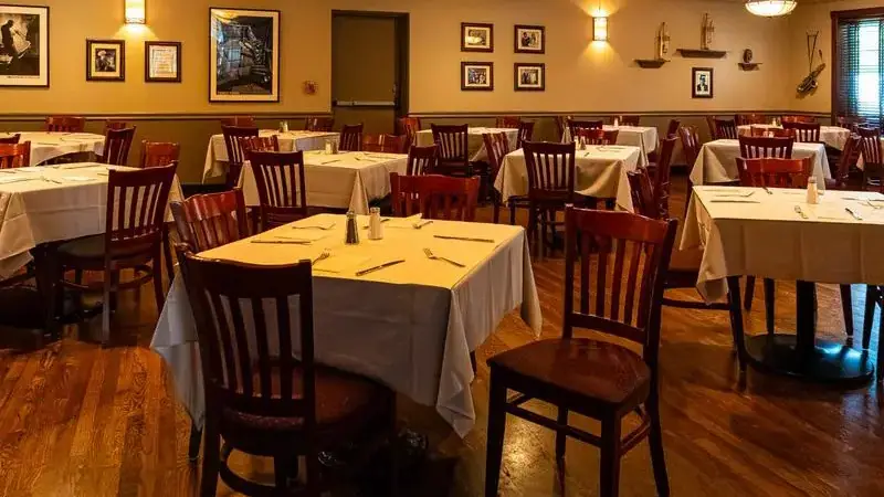 Palmer's dining room with white tablecloths, wooden chairs, a wood floor and warm wall lights