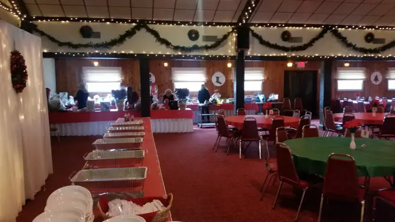 The club's wood-paneled banquet room decorated for the holidays, with a buffet line and round tables in red and green cloths