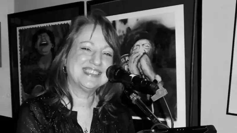 Black-and-white photo of Radio Active's keyboard player smiling while she plays and sings