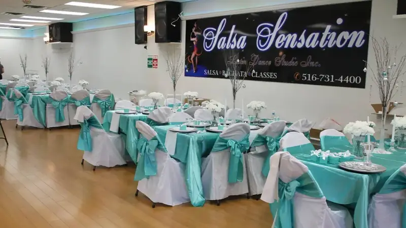 Studio set up for a party with teal and white tables under the black 'Salsa Sensation Latin Dance Studio' sign