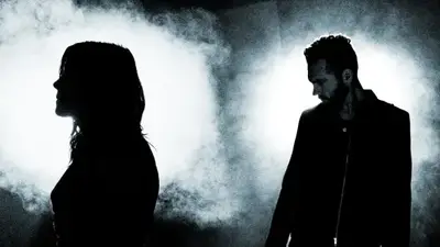 Wide black-and-white promo image of the four members of Skillet as silhouettes against bright backlights