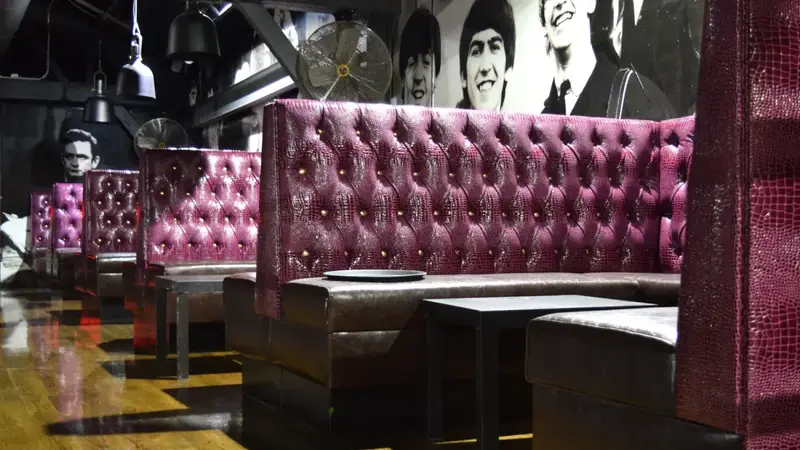 Tall pink tufted leather booths in the Stereo Garden lounge, with a large black and white mural of musicians on the wall
