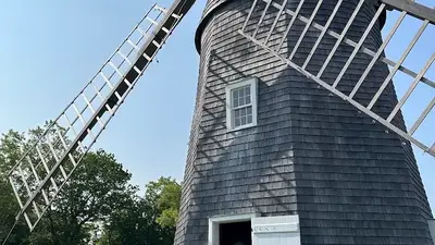 Visitors standing outside the open door of the shingled 1810 windmill at Sylvester Manor