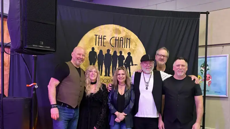 The members of The Chain standing in front of their moon logo backdrop with candles on stage