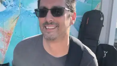 NuGroove Project guitarist in sunglasses smiling while playing a white electric guitar outdoors in the sun